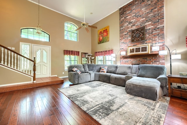 living area with ornamental molding, stairway, a high ceiling, wood-type flooring, and baseboards