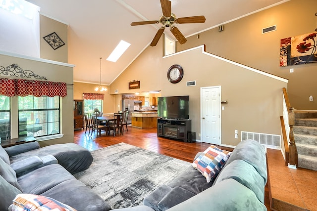 living area with visible vents, ceiling fan, high vaulted ceiling, and stairs