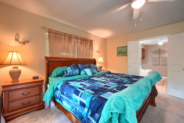 bedroom with light carpet, ensuite bath, a ceiling fan, and a textured ceiling