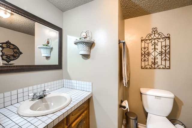bathroom with vanity, a textured ceiling, backsplash, and toilet