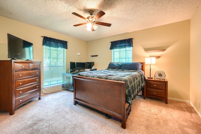 bedroom with a ceiling fan, multiple windows, carpet flooring, and a textured ceiling