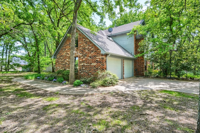 view of home's exterior featuring a garage, brick siding, driveway, and a shingled roof