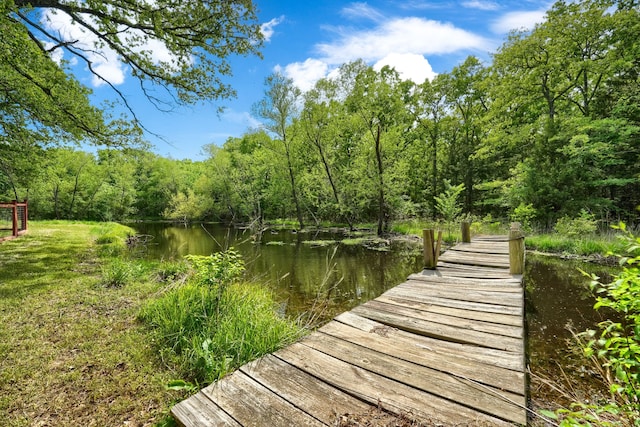 dock area featuring a wooded view and a water view