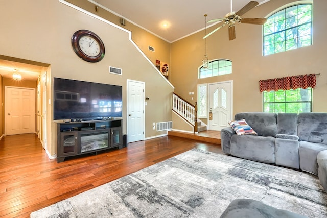 living area featuring hardwood / wood-style floors, a healthy amount of sunlight, visible vents, and stairway