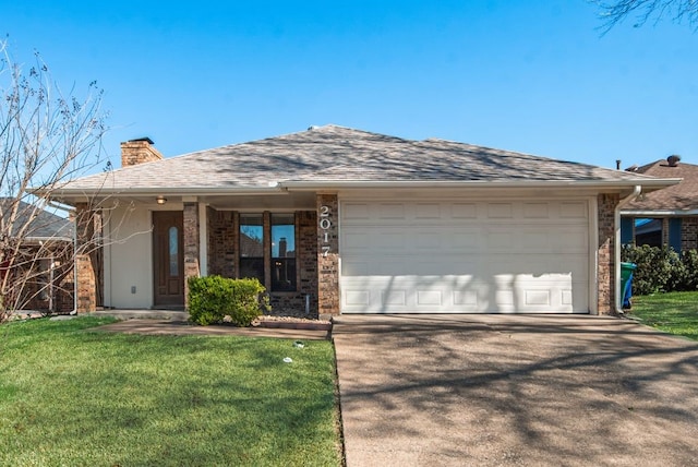 view of front facade featuring an attached garage, a chimney, brick siding, a front lawn, and driveway