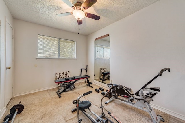workout room featuring baseboards, a textured ceiling, light colored carpet, and ceiling fan