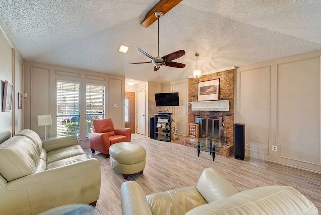 living area featuring lofted ceiling with beams, a textured ceiling, ceiling fan, a decorative wall, and wood finished floors