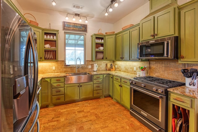 kitchen with a sink, open shelves, green cabinetry, and stainless steel appliances
