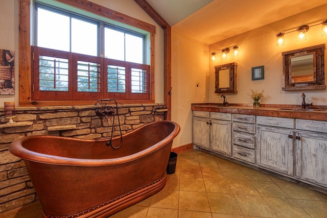 bathroom featuring a soaking tub, tile patterned flooring, a sink, lofted ceiling, and double vanity
