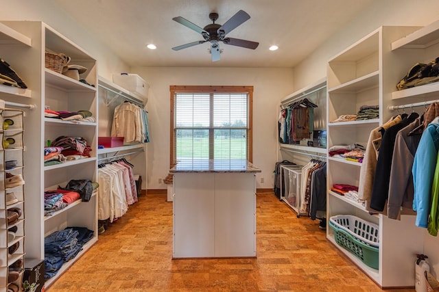 walk in closet featuring a wall mounted AC, light wood-type flooring, and a ceiling fan