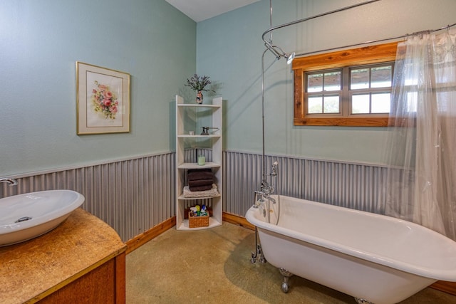 bathroom with a soaking tub, vanity, and a wainscoted wall