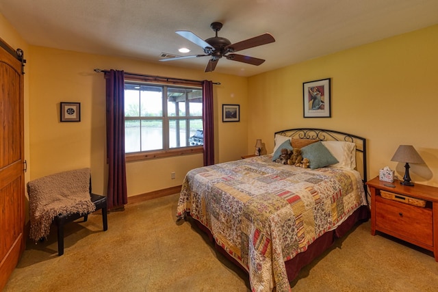 carpeted bedroom with visible vents, ceiling fan, a barn door, and baseboards
