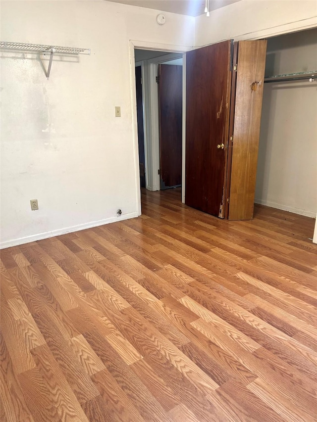 unfurnished bedroom with a closet, baseboards, and wood finished floors