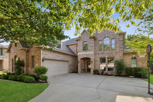 french country inspired facade with driveway, roof with shingles, brick siding, a front lawn, and an attached garage