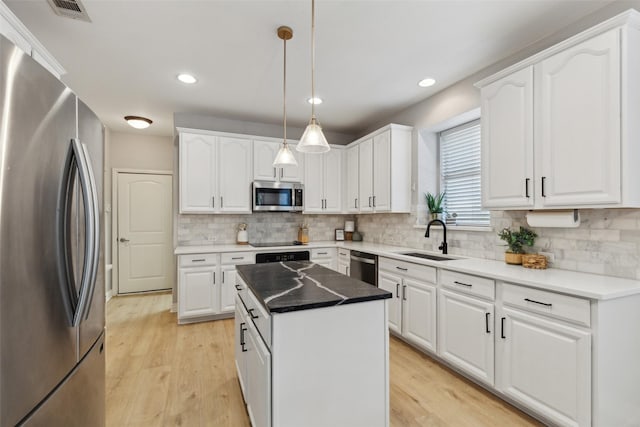 kitchen featuring a sink, a center island, stainless steel appliances, and light wood-style flooring