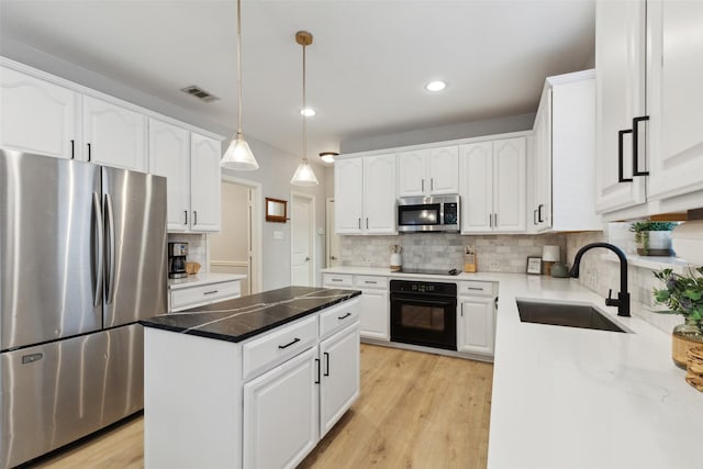 kitchen featuring a sink, a center island, backsplash, visible vents, and black appliances