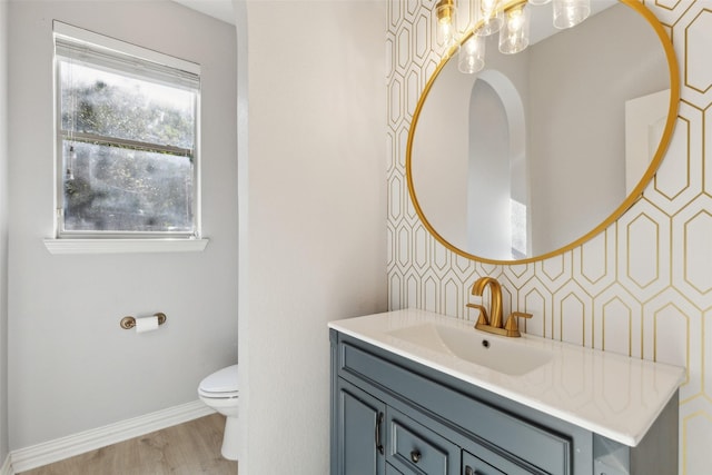 half bathroom with vanity, toilet, baseboards, wood finished floors, and backsplash