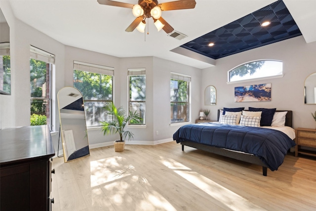 bedroom with baseboards, multiple windows, light wood finished floors, and visible vents
