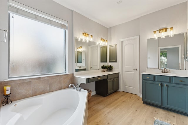 full bathroom featuring plenty of natural light, wood finished floors, a bath, and vanity
