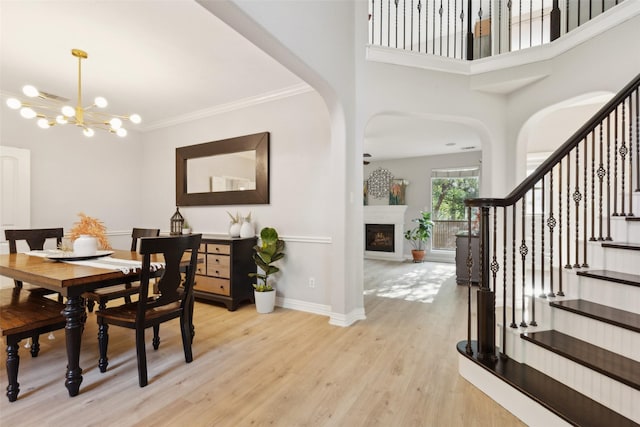 dining space featuring ornamental molding, wood finished floors, baseboards, a chandelier, and arched walkways