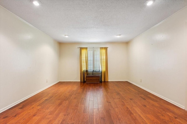 empty room with baseboards, recessed lighting, hardwood / wood-style floors, and a textured ceiling