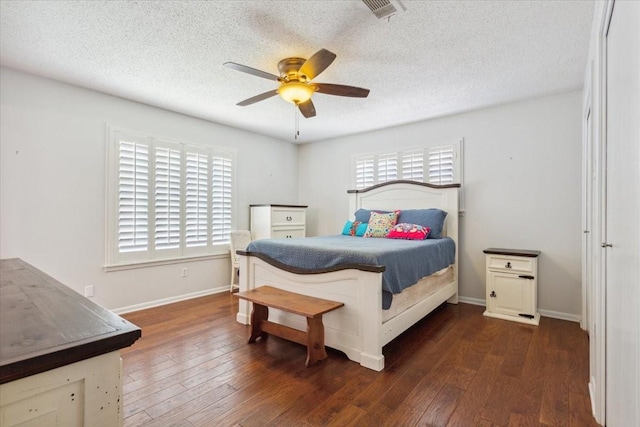 bedroom featuring visible vents, a textured ceiling, baseboards, and dark wood finished floors