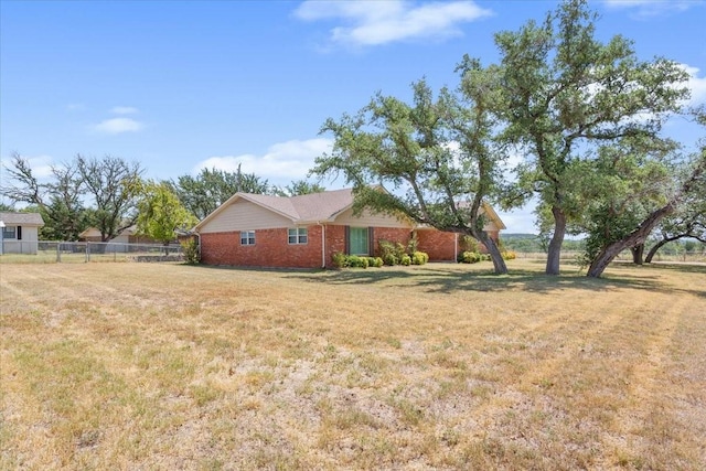 view of side of property with brick siding, fence, and a lawn