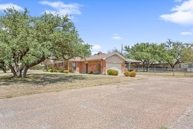 ranch-style home featuring fence, brick siding, an attached garage, a chimney, and driveway