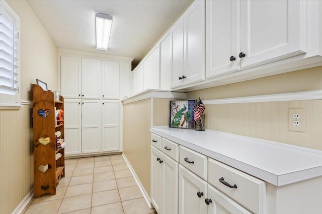 laundry room featuring light tile patterned floors, a wainscoted wall, and baseboards