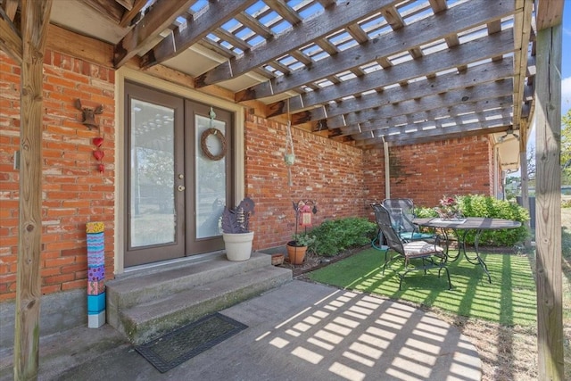 property entrance featuring brick siding, french doors, a patio area, and a pergola