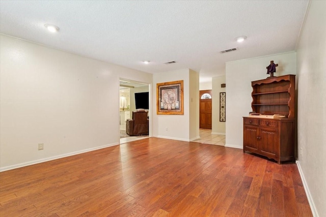 unfurnished living room with visible vents, baseboards, and wood finished floors