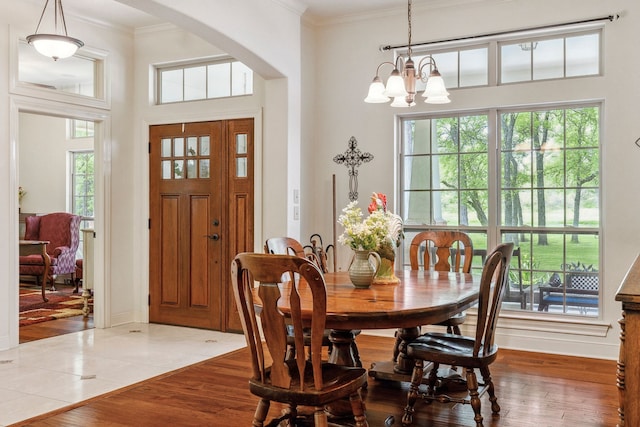 dining area with arched walkways, a notable chandelier, ornamental molding, and plenty of natural light