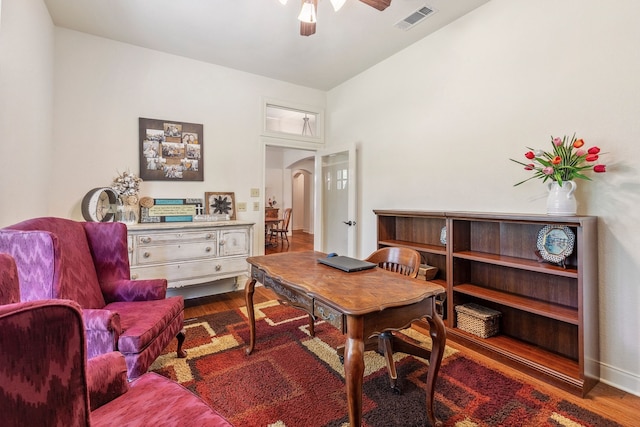 office space with arched walkways, wood finished floors, a ceiling fan, and visible vents
