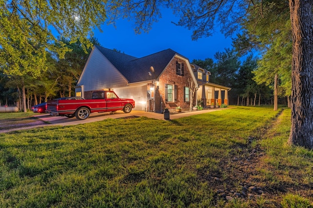 view of side of home featuring brick siding, an attached garage, driveway, and a lawn