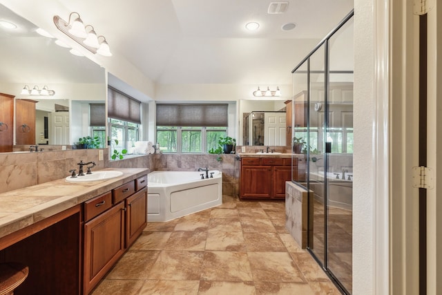 full bathroom with two vanities, vaulted ceiling, a garden tub, a shower stall, and a sink