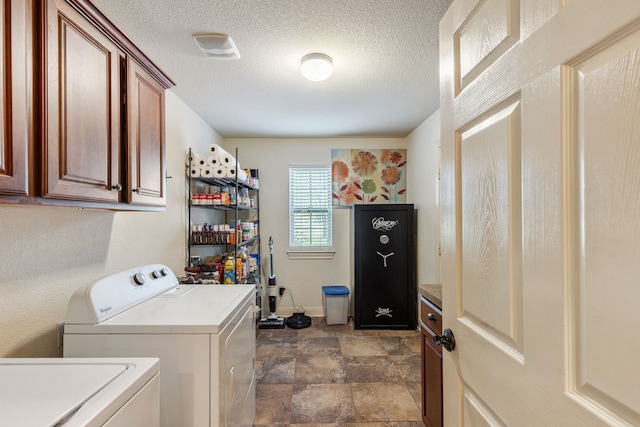 clothes washing area featuring baseboards, a textured ceiling, cabinet space, stone finish flooring, and washer and dryer