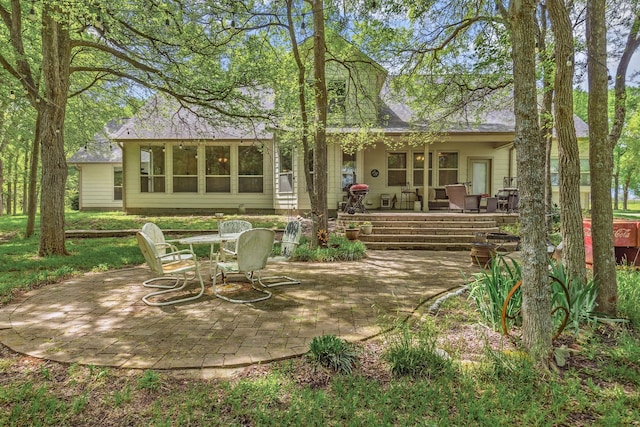 rear view of house featuring a patio and roof with shingles