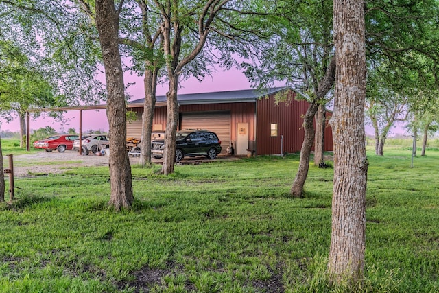 view of yard with driveway, an outdoor structure, an outbuilding, and a detached garage