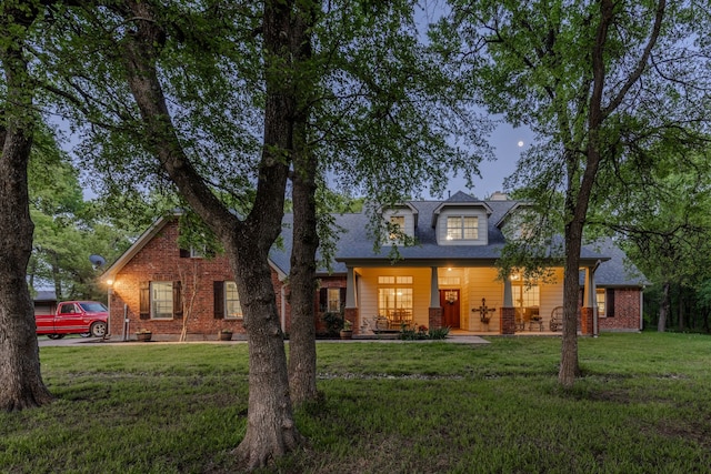 view of front facade featuring a porch, a front lawn, and brick siding