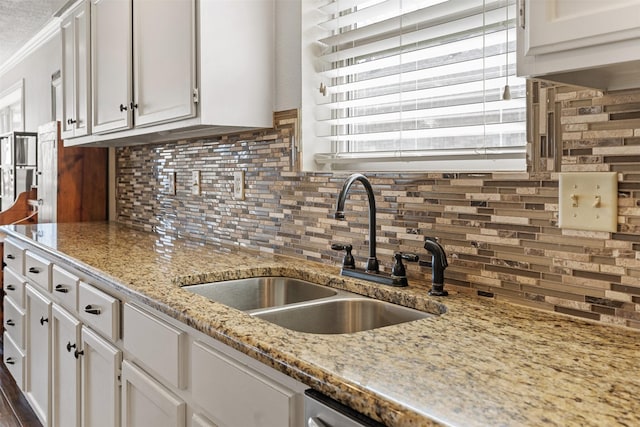 kitchen featuring a sink, backsplash, white cabinetry, and plenty of natural light