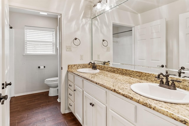 full bathroom featuring a sink, baseboards, wood finished floors, and toilet
