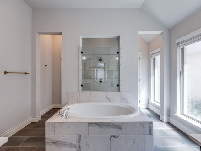 bathroom with a shower stall, a garden tub, baseboards, and vaulted ceiling