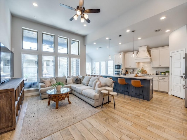 living area with recessed lighting, a high ceiling, light wood-style floors, visible vents, and ceiling fan