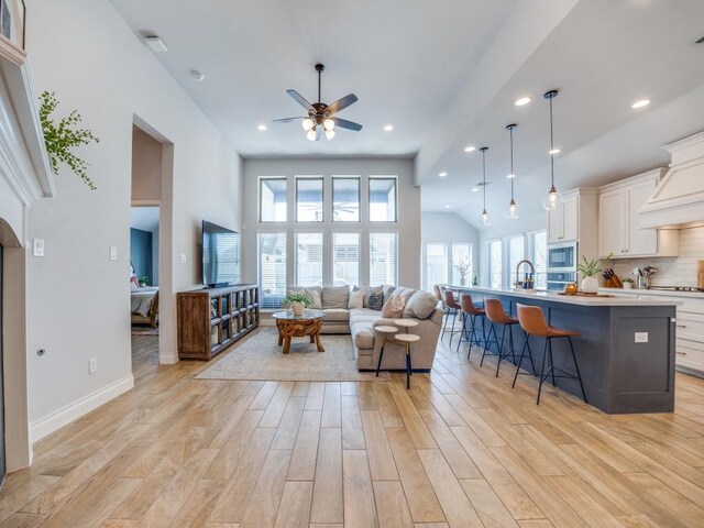living room featuring light wood-style floors, ceiling fan, baseboards, and a healthy amount of sunlight