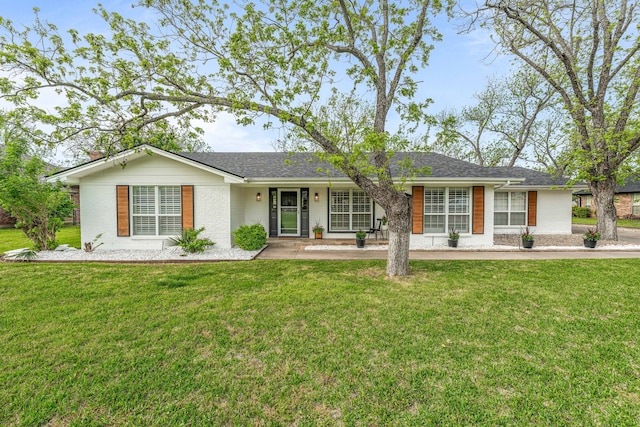 ranch-style house with a shingled roof, a front yard, and brick siding