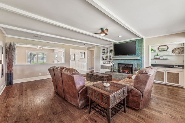 living room featuring baseboards, a fireplace, visible vents, beam ceiling, and wood finished floors