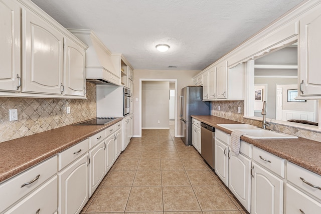 kitchen with light tile patterned floors, white cabinets, a sink, stainless steel appliances, and backsplash
