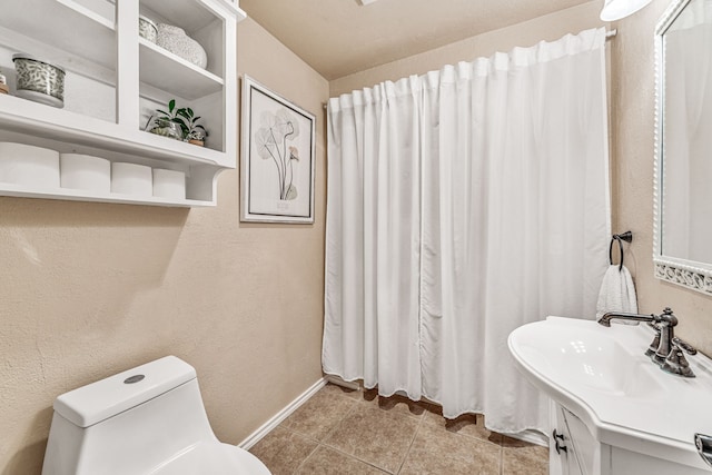 bathroom featuring tile patterned floors, vanity, baseboards, and toilet