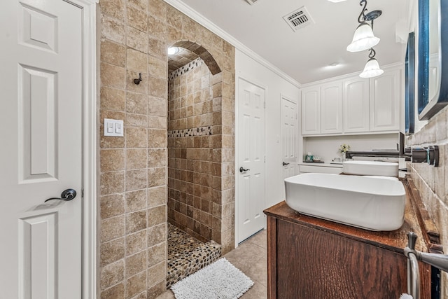 full bathroom with visible vents, ornamental molding, vanity, tile patterned floors, and tiled shower