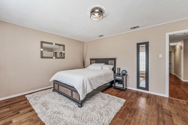 bedroom with visible vents, baseboards, and wood finished floors